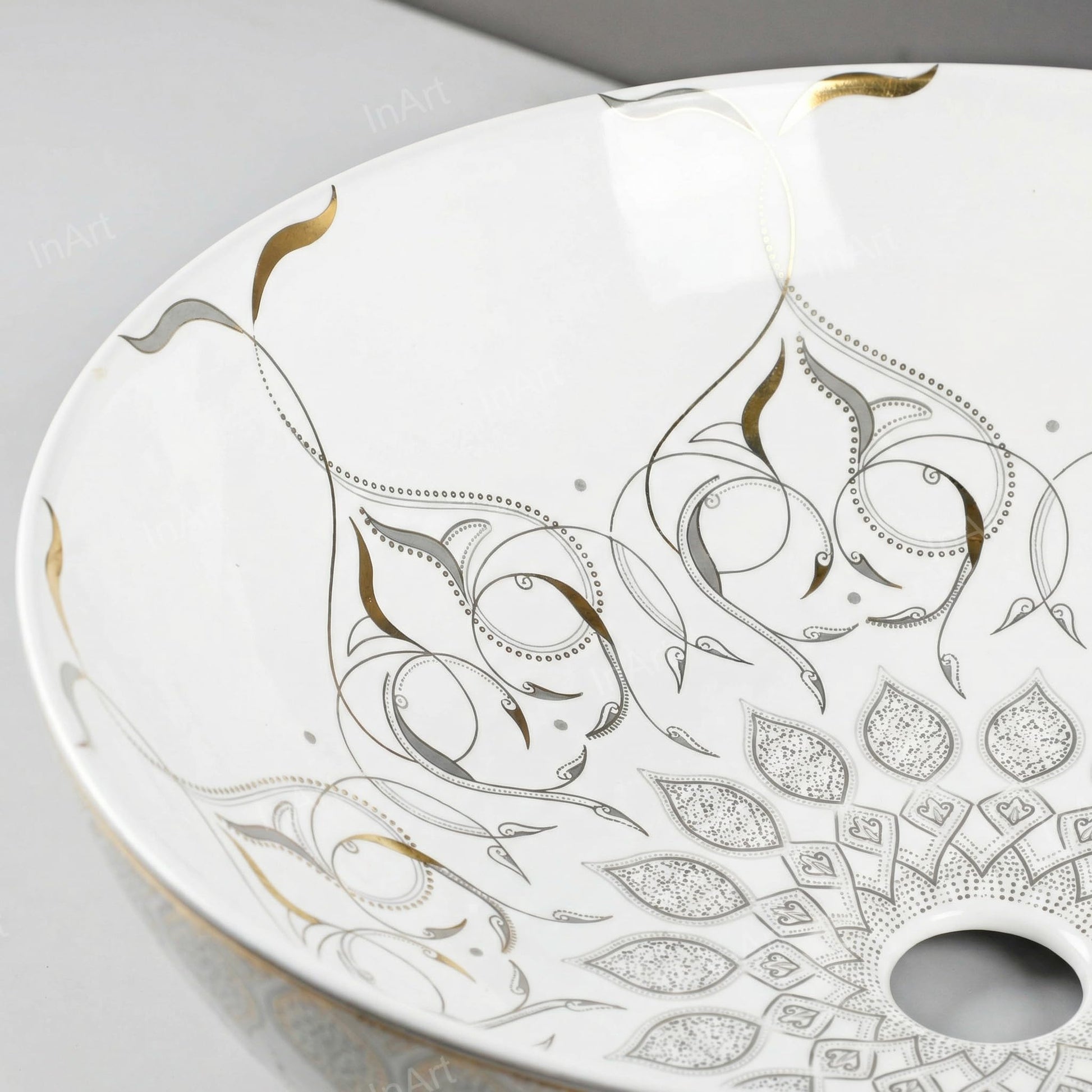 Ceramic vessel sink drain opening detail, glossy white round above counter sink with gold edge