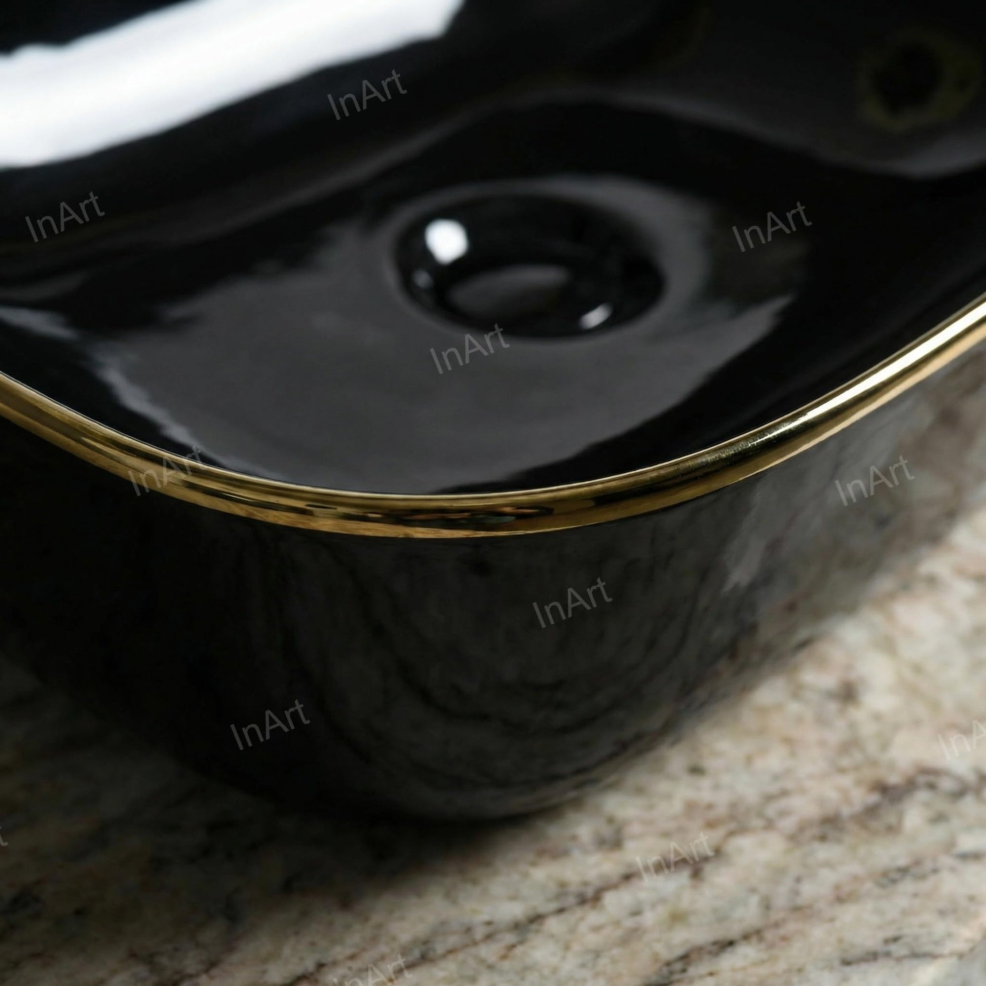 Glossy finish detail on black and gold ceramic bathroom sink, rectangular tabletop vessel basin rim close-up