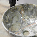 Bathroom sink on top of vanity lifestyle with round ceramic vessel sink, green marble finish and faucet pairing